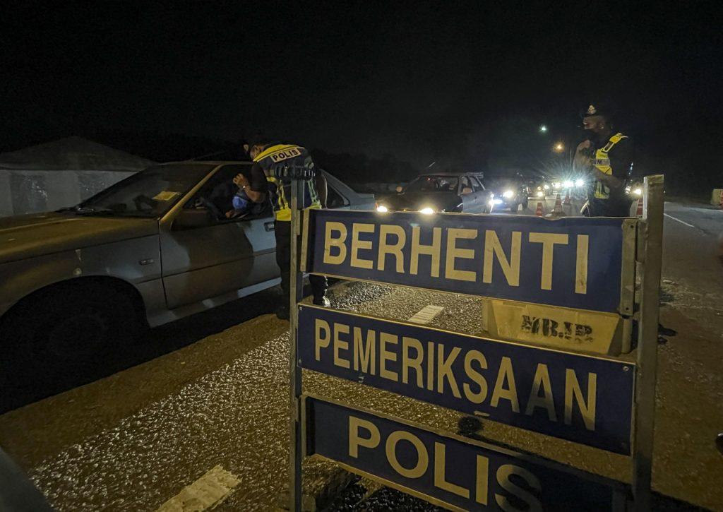 Police officers check the travel documents of drivers at a roadblock in Kota Tinggi, Johor. Photo: Bernama