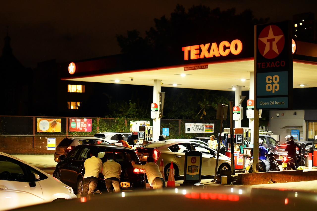 People push a car, which has run out of petrol, the final few metres on to the forecourt as vehicles queue to refill at a Texaco fuel station in south London, Britain, Sept 26. Photo: Reuters
