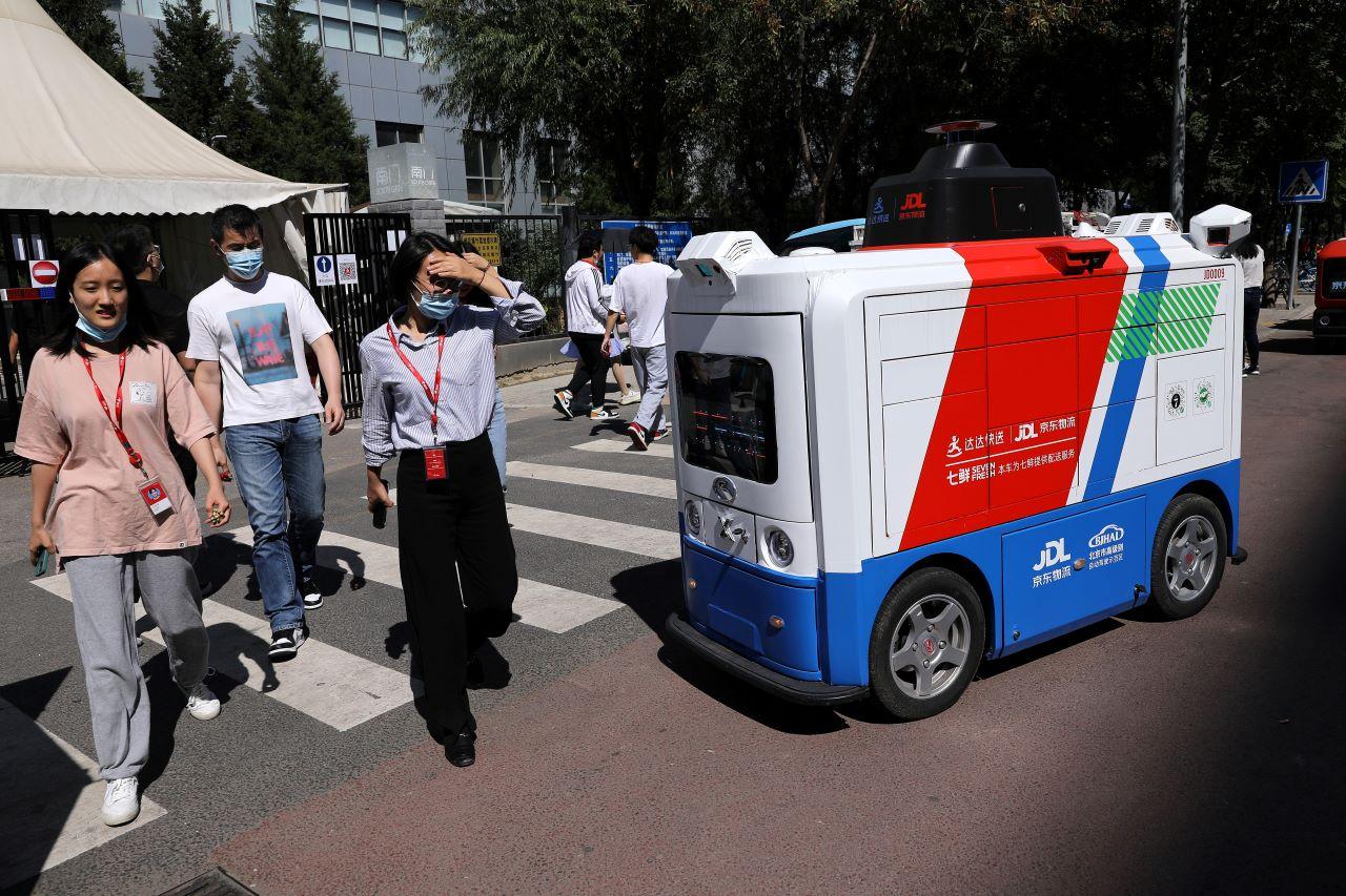 People walk past an autonomous delivery vehicle by JD Logistics, the delivery arm of JD.com, as it operates on a street in Beijing, China Sept 22. Photo: Reuters