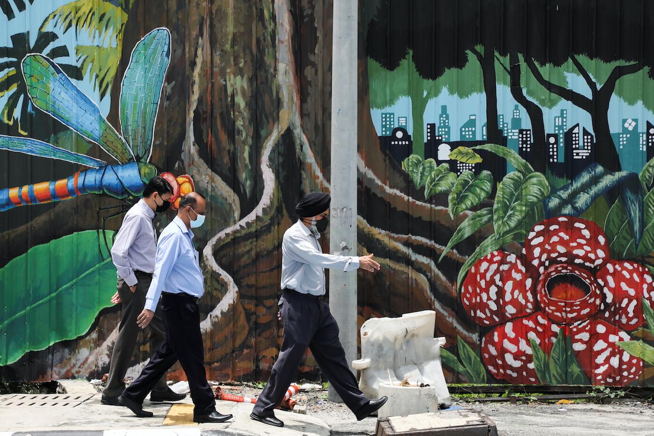 Office workers wearing protective face masks walk past a mural in Kuala Lumpur, Sept 27. Photo: Reuters
