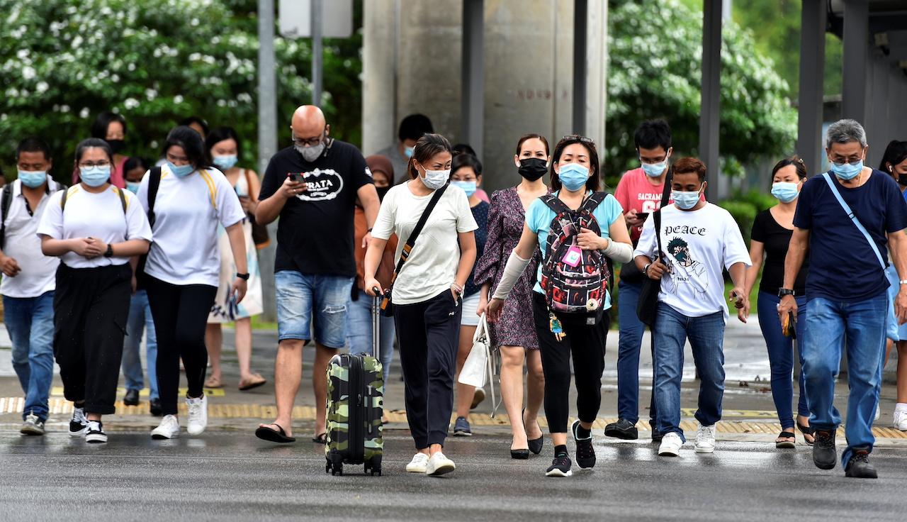FILE PHOTO: People wearing face masks cross a road amid the coronavirus disease (COVID-19) outbreak in Singapore