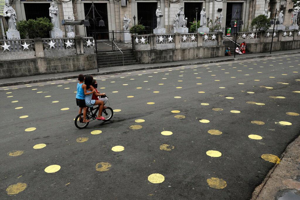 Children ride a bike past markers placed outside the Santo Nino Parish at Tondo district, Manila, Philippines on Jan 15. Seven of 10 victims of rape in the Philippines are children, data from the Center for Women's Resources shows. Photo: Reuters