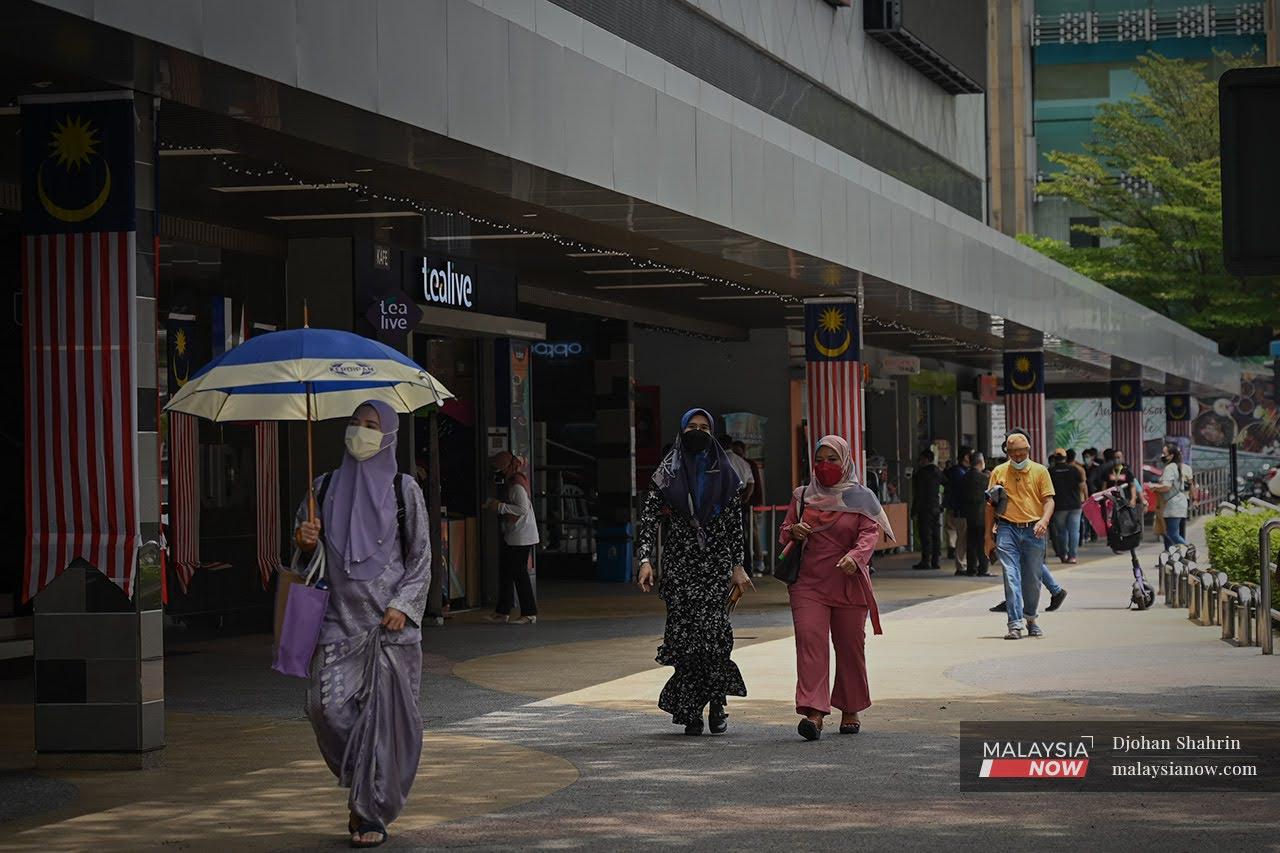 Pedestrians wearing face masks walk along Jalan Tuanku Abdul Rahman in Kuala Lumpur.