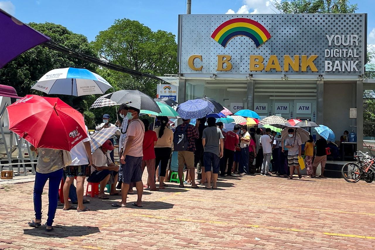 FILE PHOTO: People line up outside a bank to withdraw cash, in Yangon