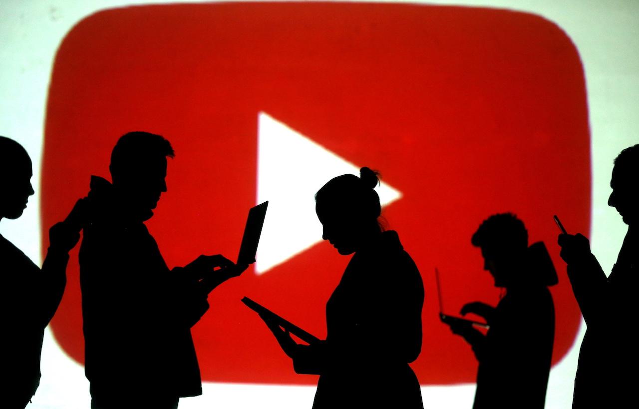 FILE PHOTO: FILE PHOTO: Silhouettes of laptop and mobile device users next to a screen projection of the YouTube logo in this picture illustration