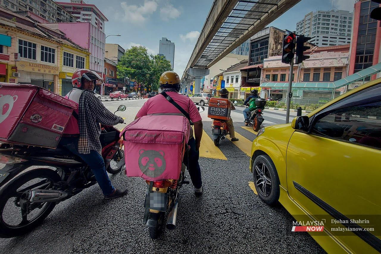 Food delivery riders, a ubiquitous sight in the capital city, wait at a traffic light in Jalan Chow Kit, Kuala Lumpur.
