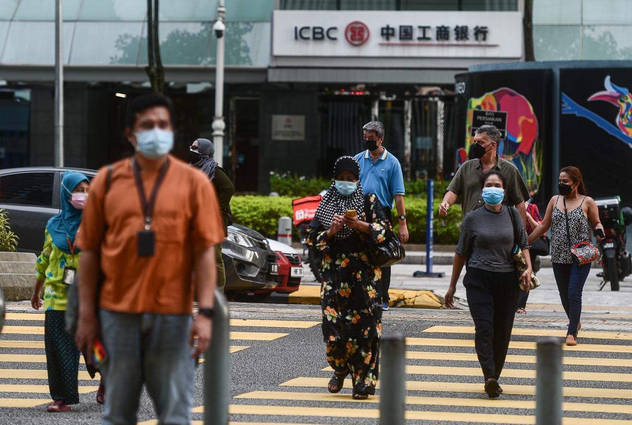 Pedestrians wearing face masks cross a road at Jalan Ampang in Kuala Lumpur. Photo: Bernama