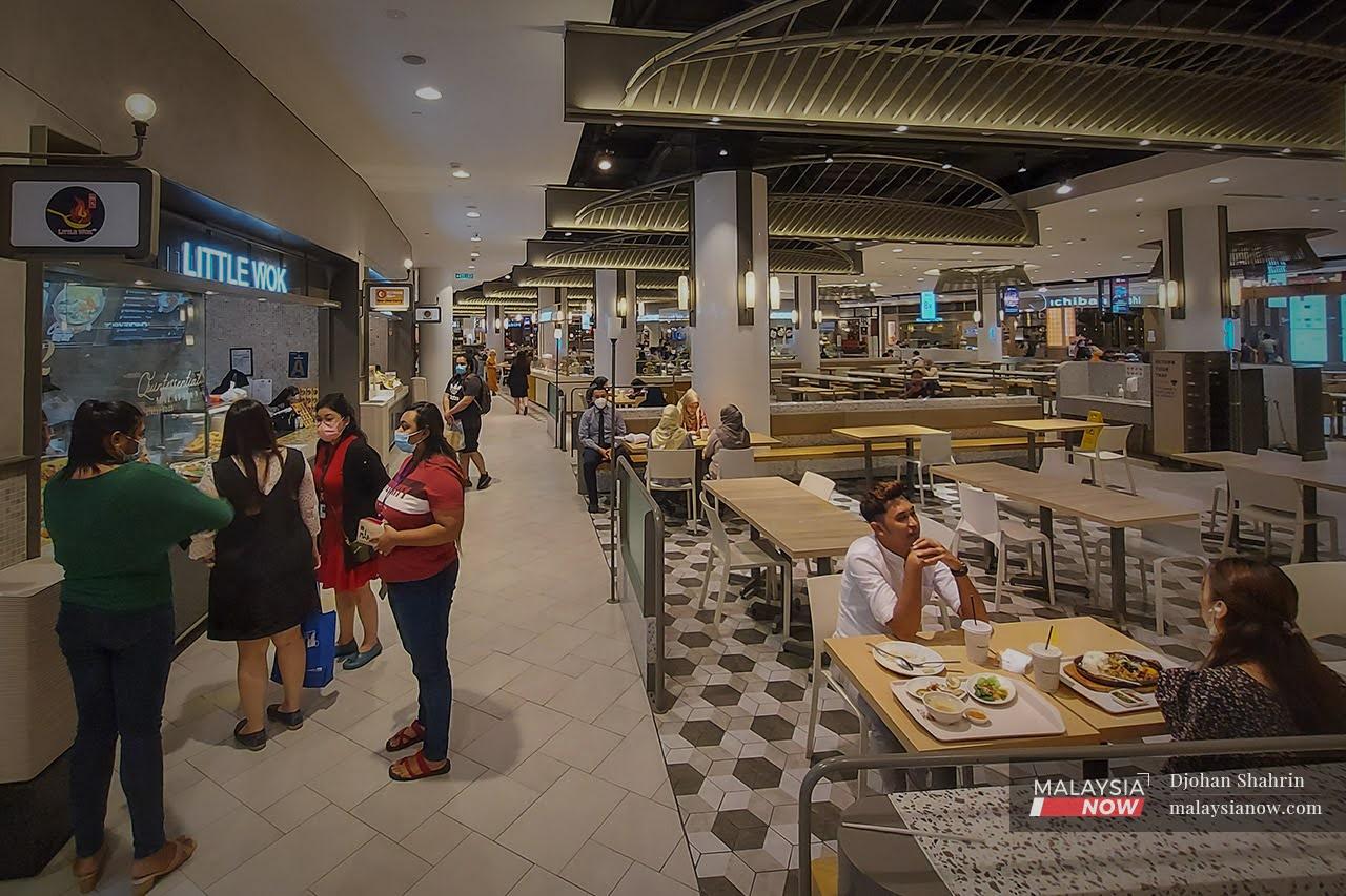 Dine-in customers wait for their orders at a food court in Bukit Bintang, Kuala Lumpur, while others enjoy their meal after restrictions on eating in were relaxed.