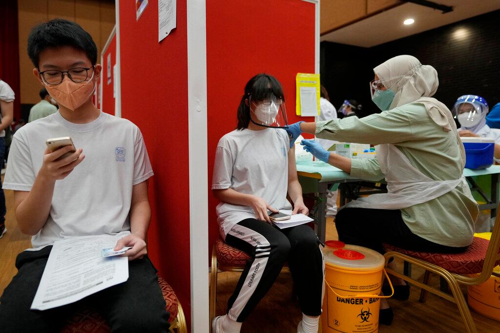A student receives a shot of Pfizer vaccine while another waits for his turn at a vaccination centre in Shah Alam, Sept 20. Photo: AP