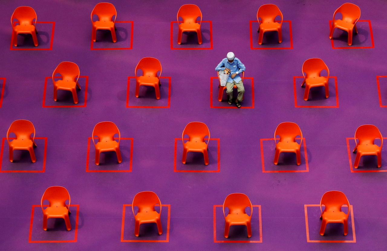 A man sits among empty seats at a free movie screening as restrictions on social gathering are tightened due to the surge of Covid-19 cases in Singapore, Sept 29. Photo: Reuters