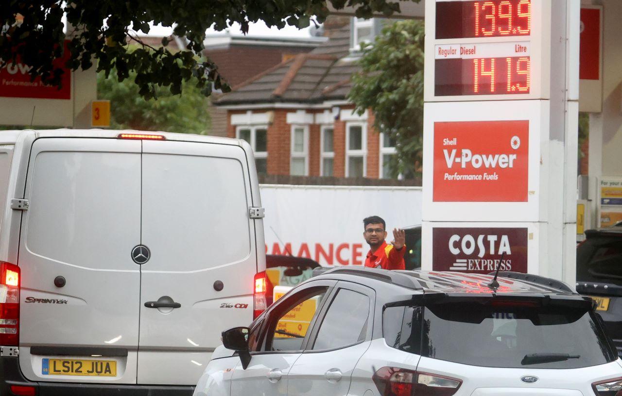 A worker guides vehicles into the forecourt as they queue to refill at a fuel station in London, Britain, Sept 30. Photo: Reuters