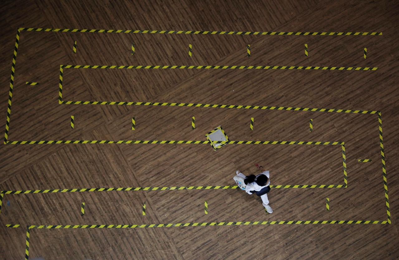 A woman walks across a line of tape demarcating social distancing in a mall in Singapore, Sept 28. Photo: Reuters