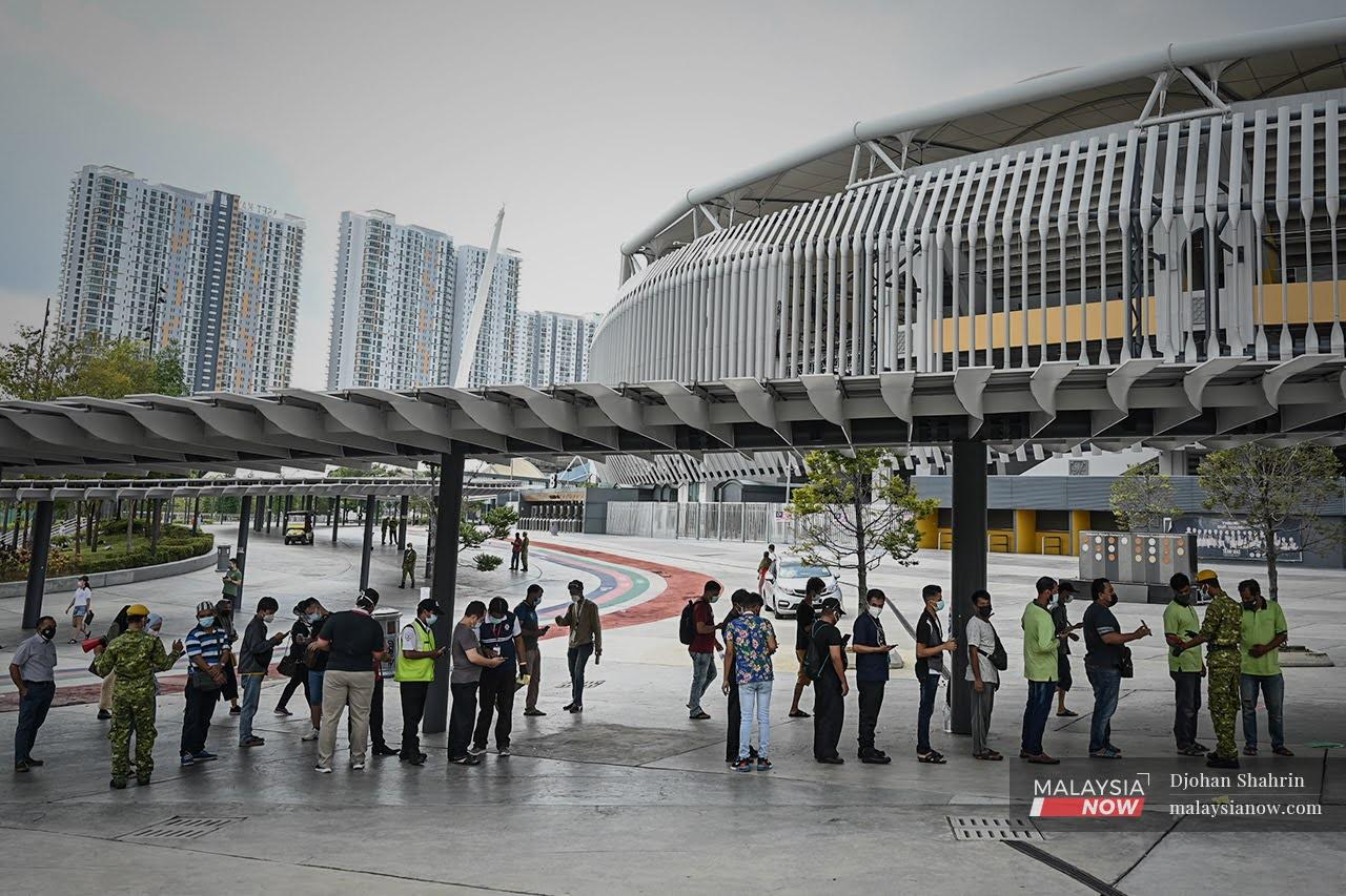 Penerima vaksin hadir secara walk-in ke pusat vaksinasi beratur menunggu giliran sebelum mendapatkan vaksin Sinovac tanpa temujanji di Stadium Bukit Jalil.