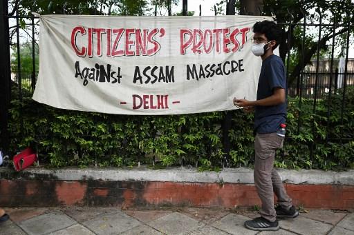 A demonstrator stands next to a banner during a protest against an eviction drive by Assam's state government on Sept 23 of Muslim families in Assam, which turned violent with the killing of two men when hundreds clashed with police, in New Delhi on Sept 25. Photo: AFP