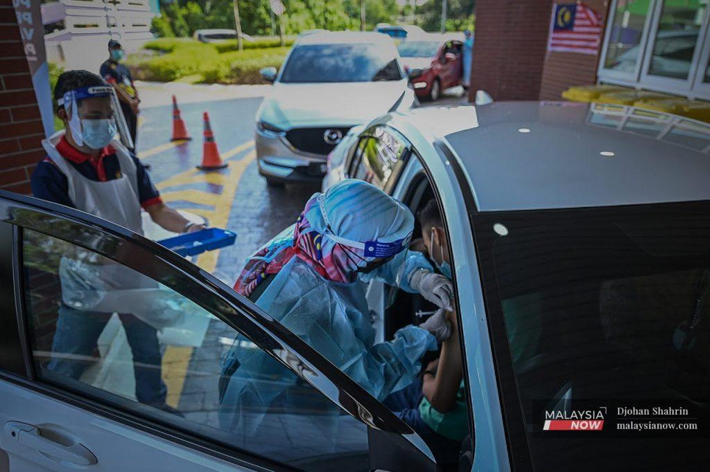 A health worker administers a shot of Covid-19 vaccine at a drive-thru vaccination centre in Cheras.