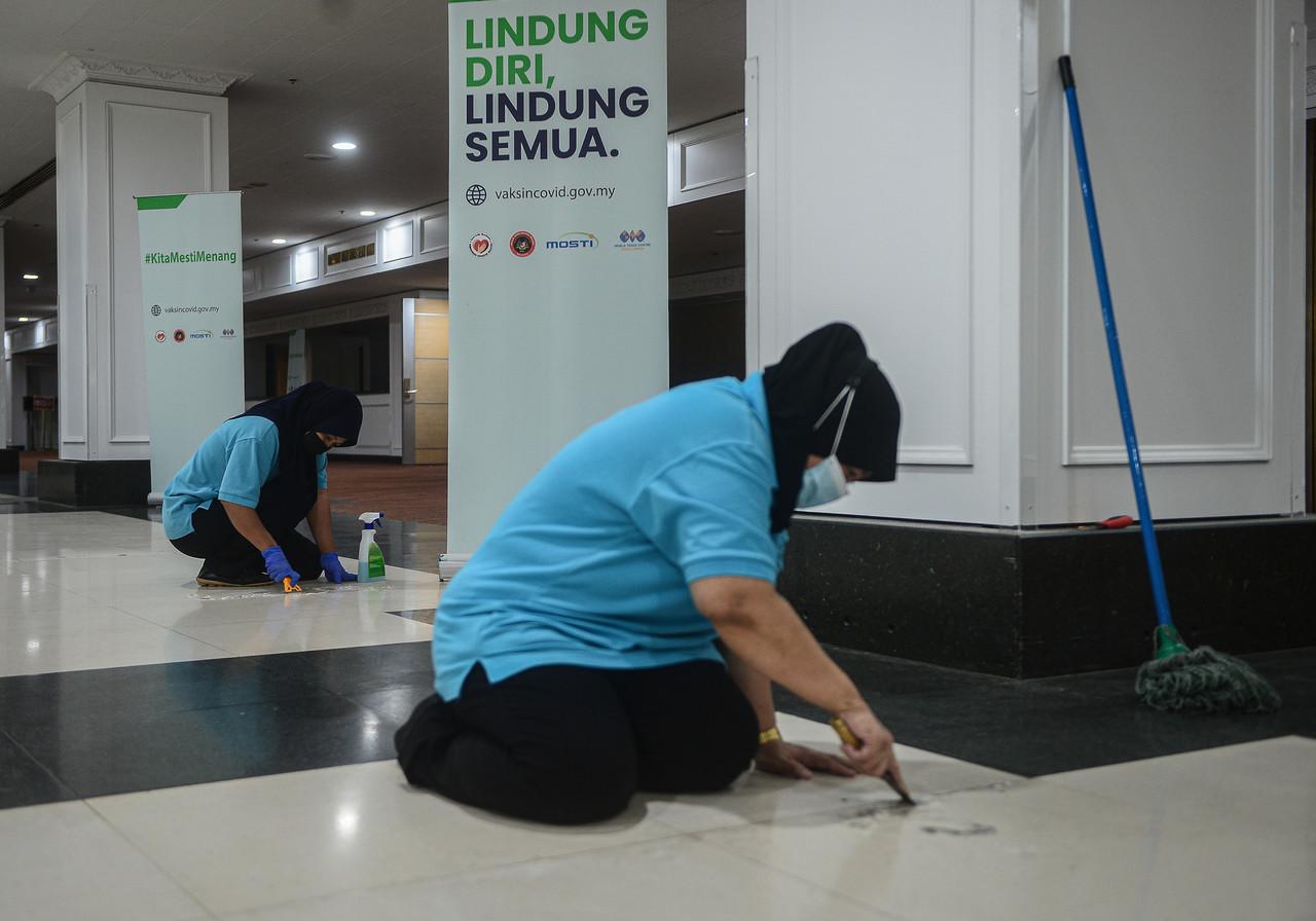 Workers clean the World Trade Centre in Kuala Lumpur, the venue of a mega vaccination centre which ceased operations yesterday after dispensing some 1.2 million doses of Covid-19 vaccine. Photo: Bernama