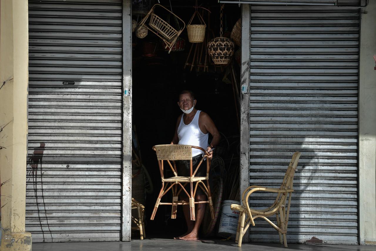 A dealer in rattan furniture begins opening his shop for the day in George Town, Penang. Photo: Bernama