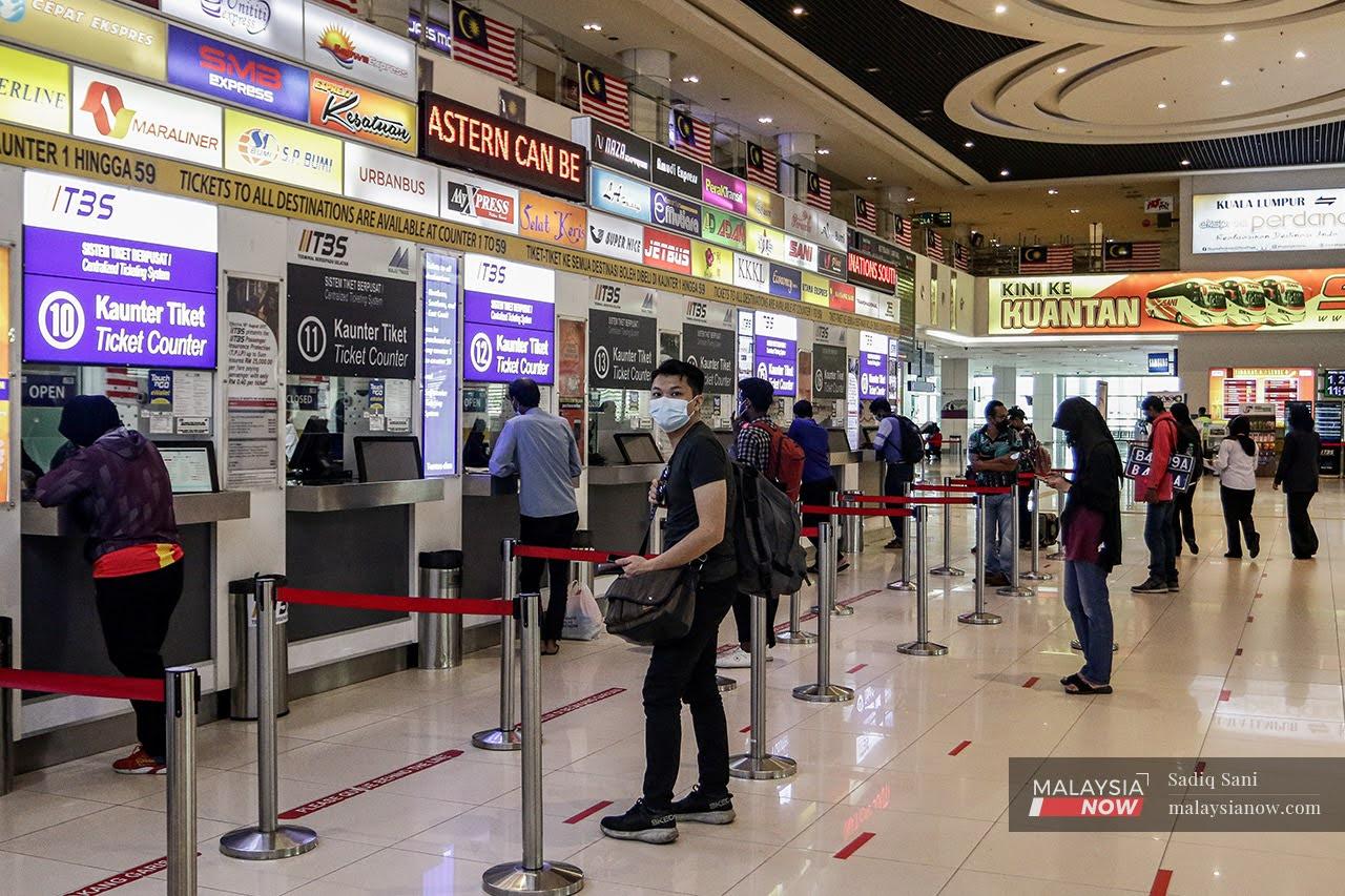 Travellers queue at the ticket counter at the Southern Integrated Terminal in Kuala Lumpur after the green light for interstate travel which took effect today.