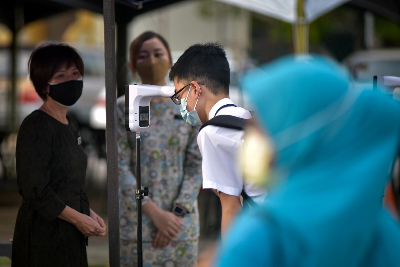 A student checks his temperature before entering the school grounds at SMK Labuan on Oct 4. Photo: Bernama