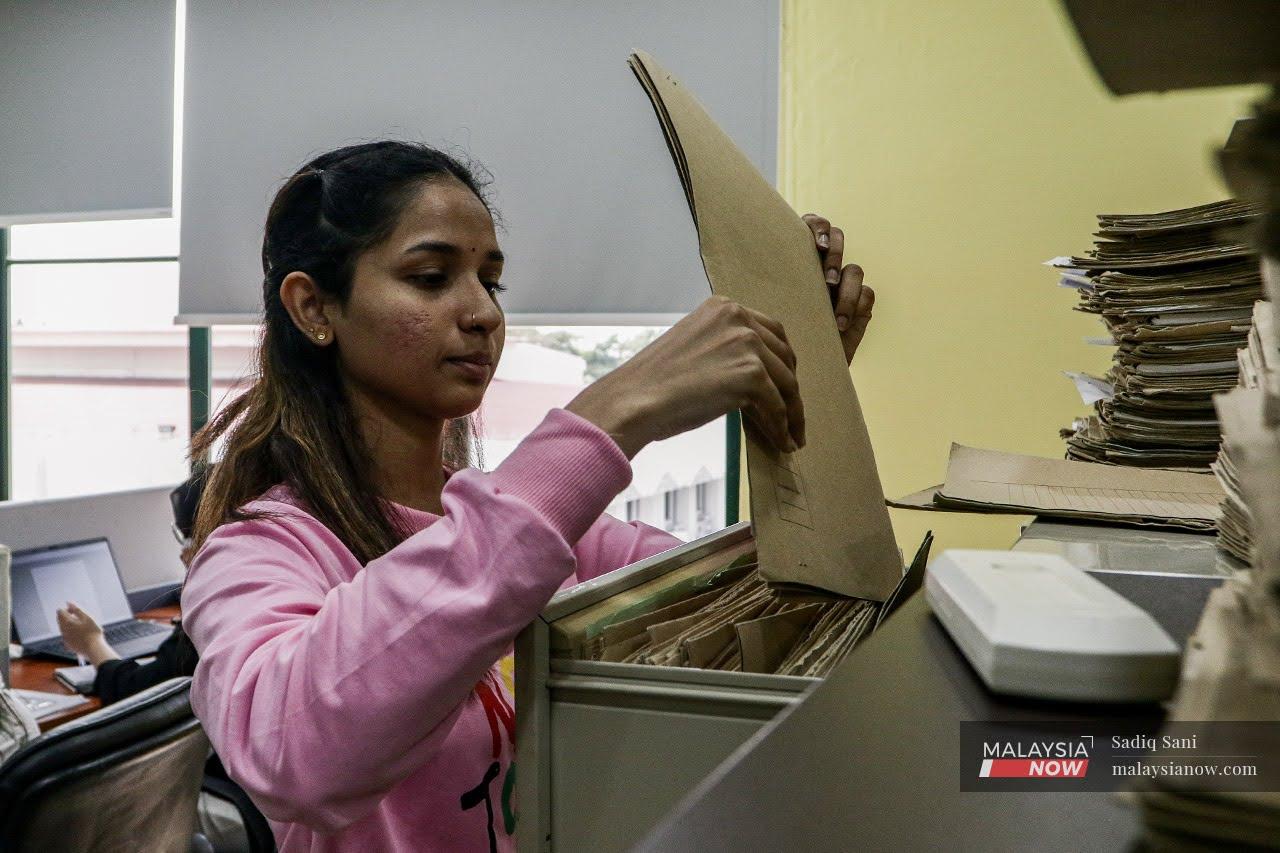 Thinesh, a young stateless woman, tidies some files at an office in Kelana Jaya where she works as a receptionist.