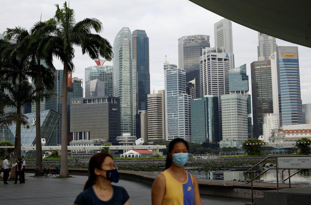 People wearing face masks pass the city skyline in Singapore, Sept 22. Singapore's economy grew 6.5% in the third quarter, broadly in line with economists' forecasts. Photo: Reuters