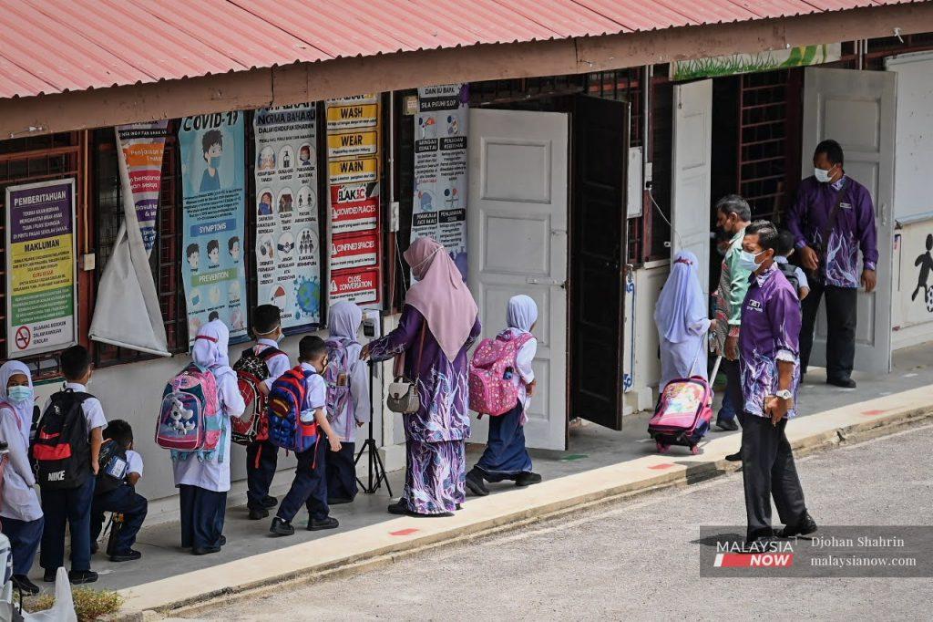 Teachers guide Standard One pupils on the first day of school in this file photo. The majority of some 37,590 teachers in Perak have been vaccinated against Covid-19.