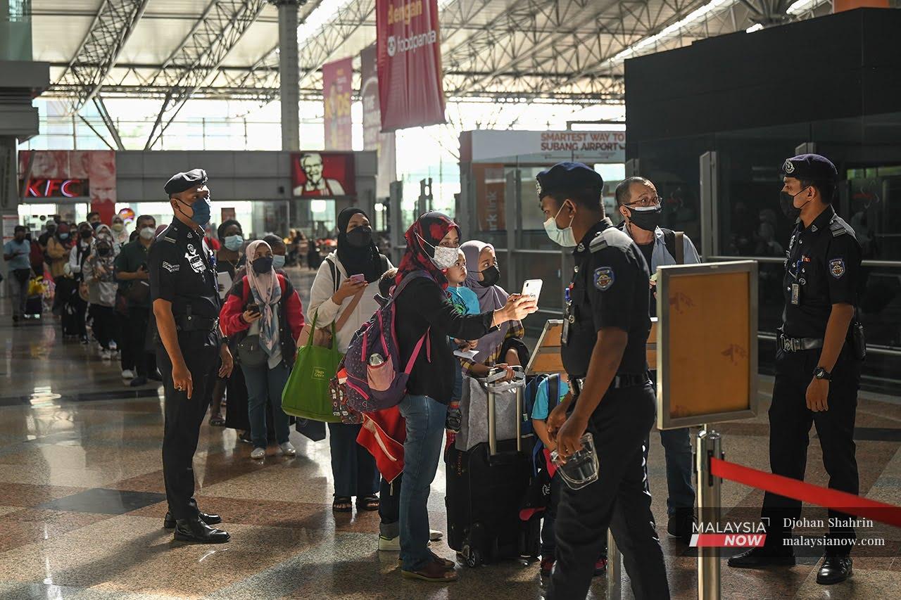 Beberapa polis bantuan Keretapi Tanah Melayu Berhad (KTMB) membuat pemeriksaan aplikasi MySejahtera kepada pelanggan yang beratur untuk memasuki ruang berlepas di stesen KL Sentral yang pulang ke kampung halaman selepas rentas negeri dibenarkan.