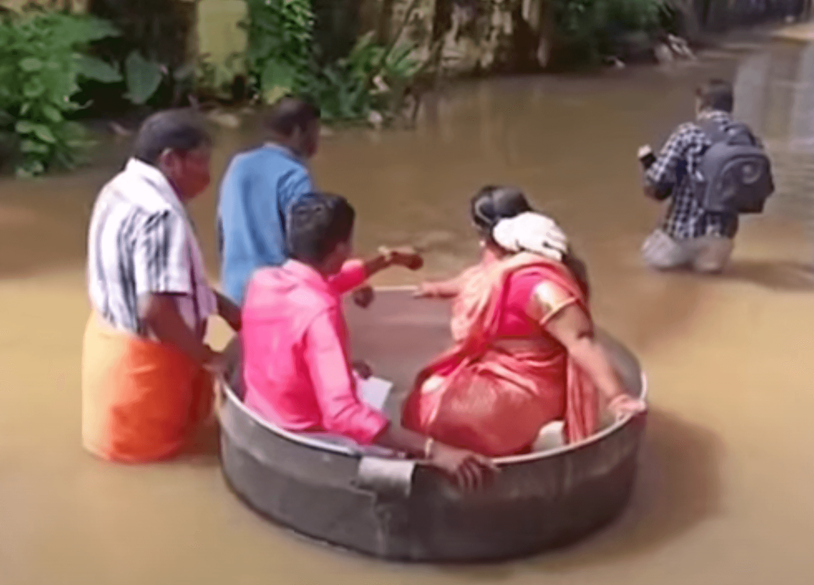 A video screenshot of a couple in India making their way to their wedding venue in a huge cooking pot, as heavy rains flood the southern state of Kerala.