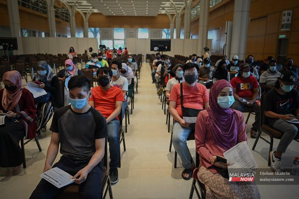 People wait for their turn to receive a shot of Covid-19 vaccine in this file picture taken at a vaccination centre in Sepang, Selangor.