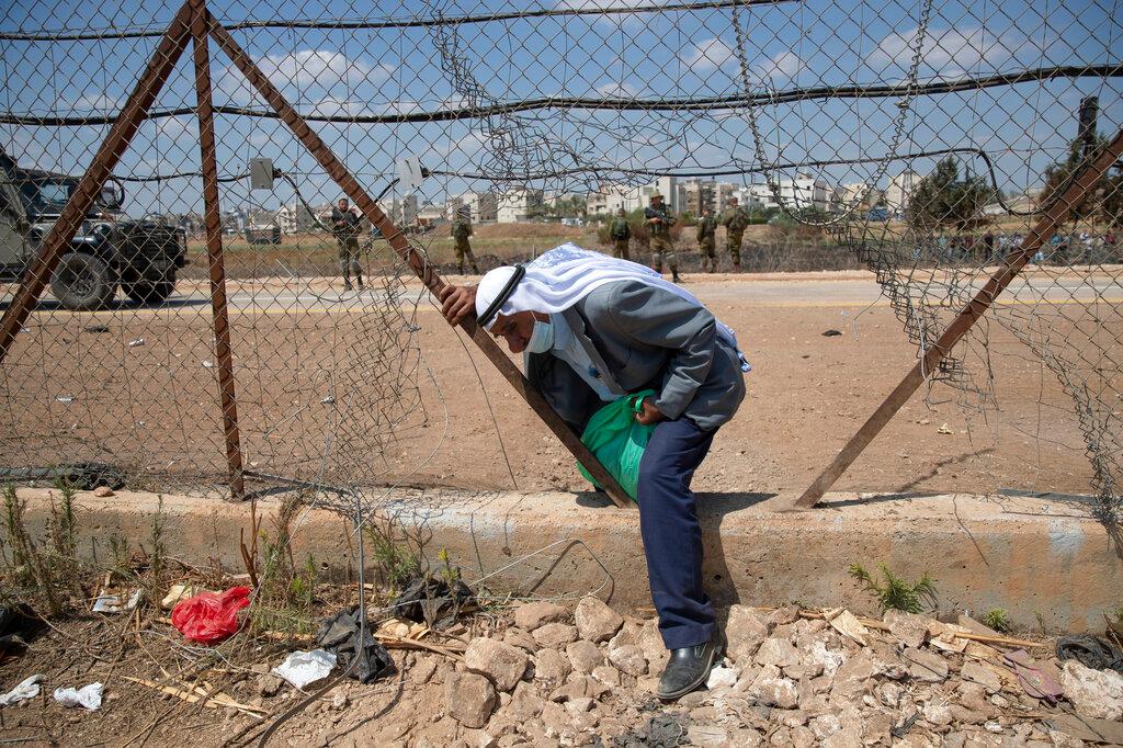 Israeli soldiers watch as a Palestinian labourer crosses through a damaged section of the Israeli separation fence, returning home after a day's work in Israel, in the West Bank village of Jalameh. Israel has said that it will grant legal residency to 4,000 Palestinians living in the occupied West Bank and Gaza, a gesture to the Palestinian Authority that will allow people who have lived under severe restrictions for years to get official IDs. Photo: AP
