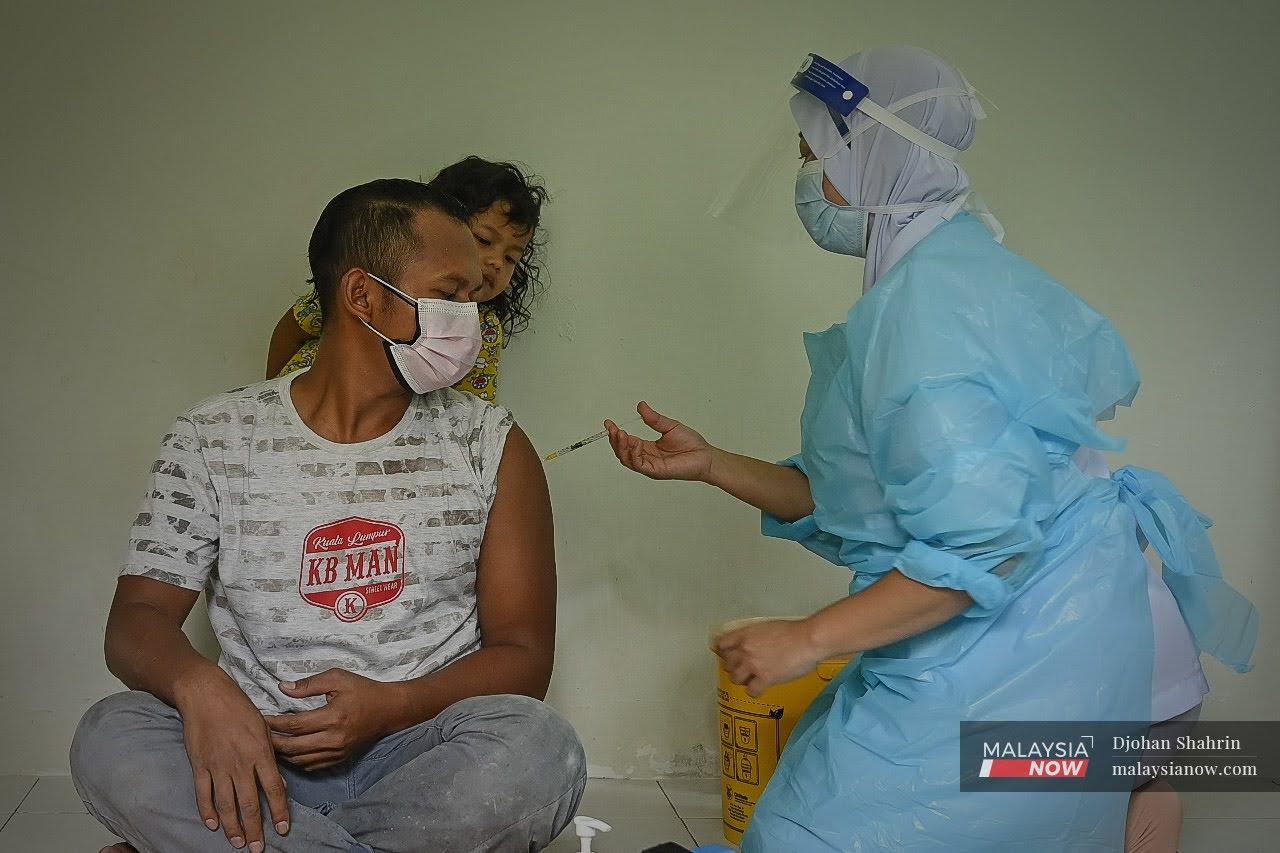 Petugas kesihatan  memberi penerangan sebelum memberi suntikan vaksin kepada Orang Asli Temuan di Kampung Orang Asli Buluh Telur, Kuala Kubu Bharu.