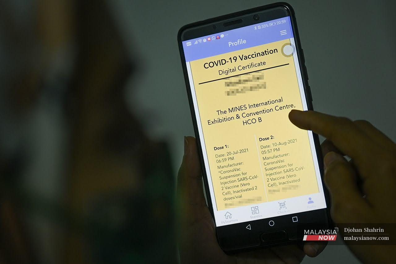 Seorang wanita menyemak sijil digital vaksinasi lengkap dalam aplikasi Mysejahtera.