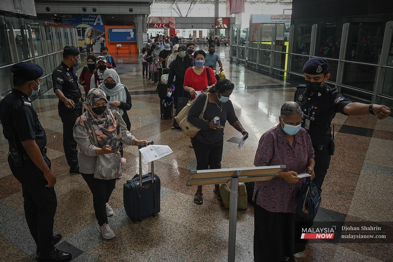 Police officers direct travellers at the KL Sentral station as movements across state borders continue following the government's move to ease restrictions for the fully vaccinated.