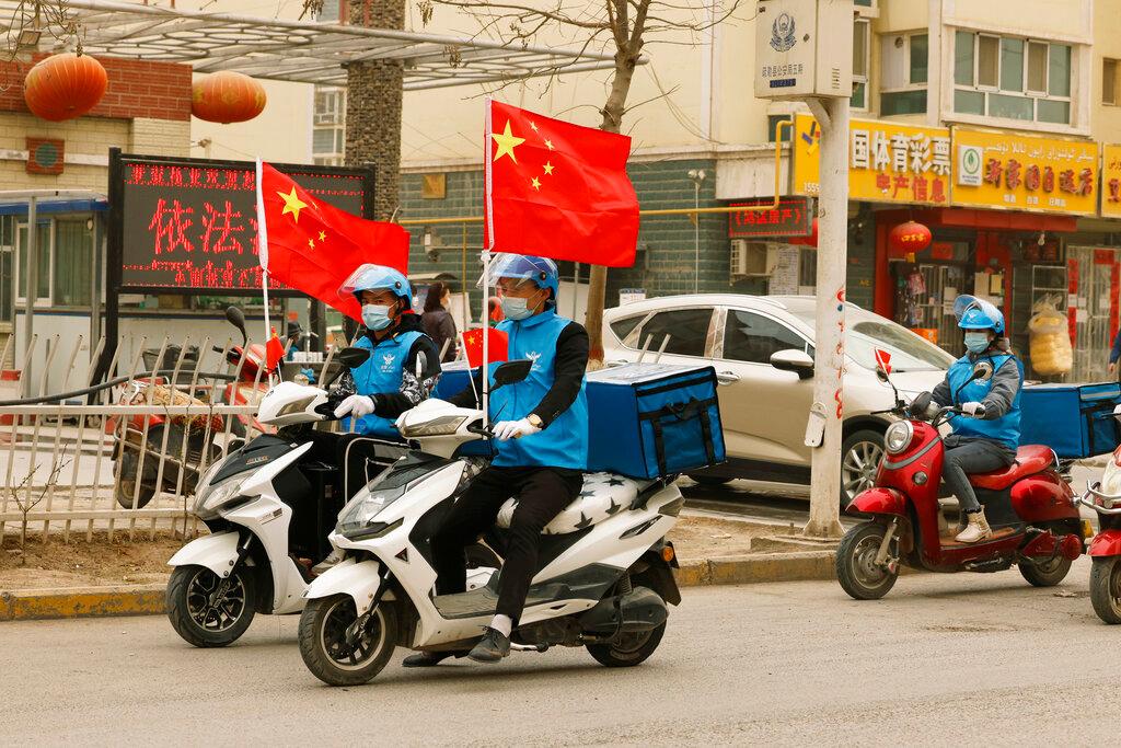 Delivery workers flying Chinese national flags ride around in a convoy to promote their services in Shule county in northwestern China's Xinjiang Uighur Autonomous Region on March 20. Photo: AP