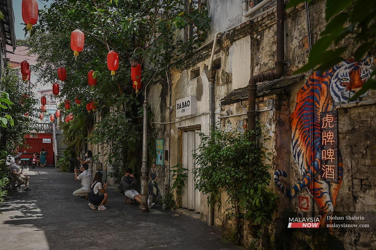 Tourists pose for photos among the brightly coloured murals and lanterns at Kwai Chai Hong in Jalan Panggung, Kuala Lumpur, as more flexibility is allowed for the fully vaccinated in social and economic sectors.