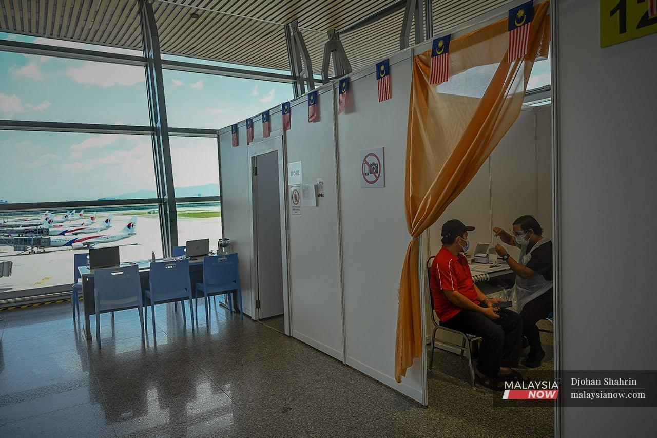 Petugas kesihatan menjalankan vaksinasi kepada pekerja-pekerja Lapangan Terbang Antarabangsa Kuala Lumpur di Sepang.