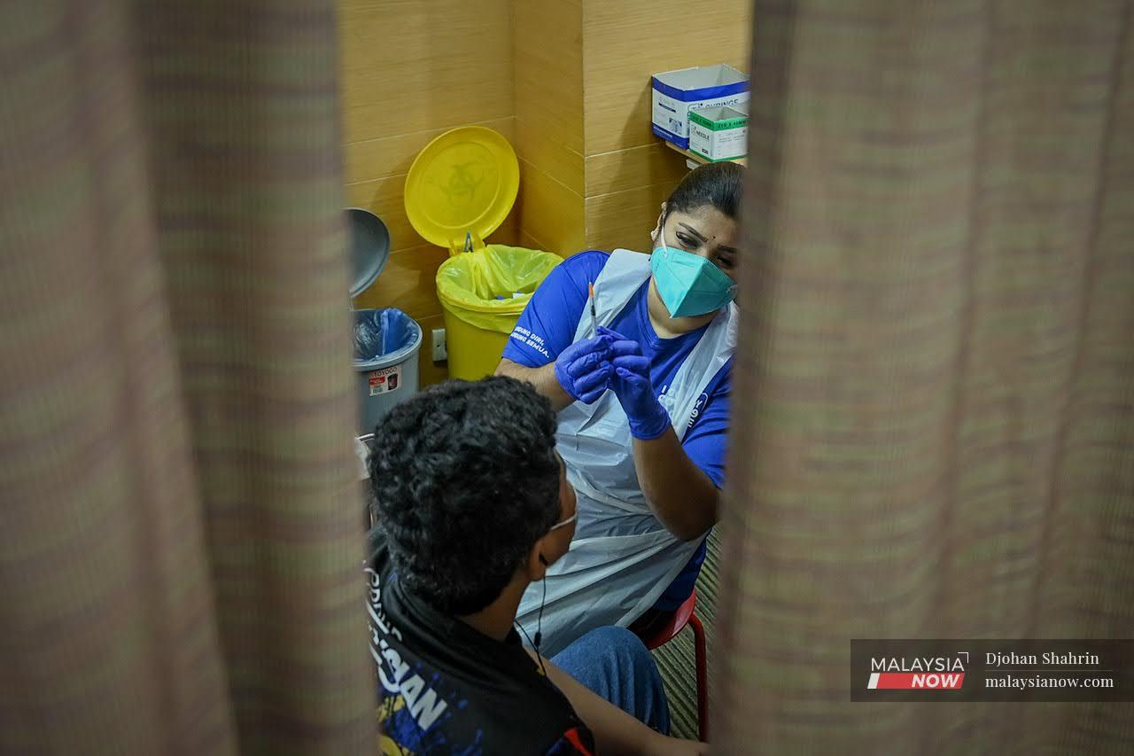 A medical worker holds up a syringe of Pfizer vaccine to show to a recipient before administering the jab at the KPJ Tawakkal vaccination centre in Jalan Pahang, Kuala Lumpur.