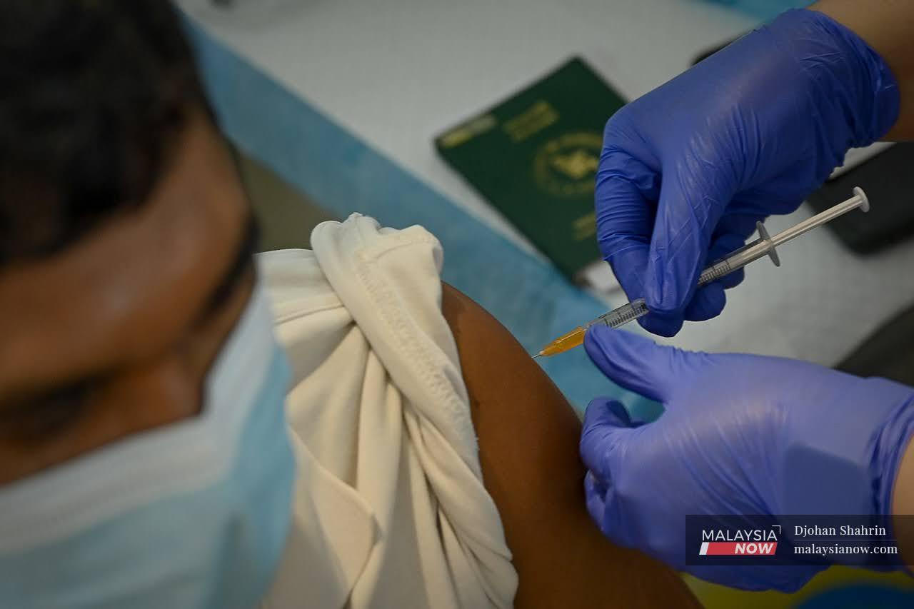Seorang pekerja asing bahagian kargo menerima vaksinasi bagi kategori industri di Lapangan Terbang Antarabangsa Kuala Lumpur, Sepang.