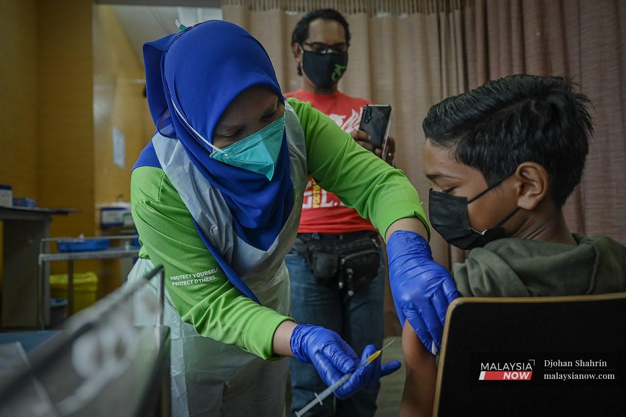 Petugas kesihatan memberi suntikan vaksin Pfizer Bio-NTech kepada Azrif Arfan Cama Adrian yang berusia 12 tahun  di Pusat Pemberian Vaksin KPJ Tawakkal, Jalan Pahang.