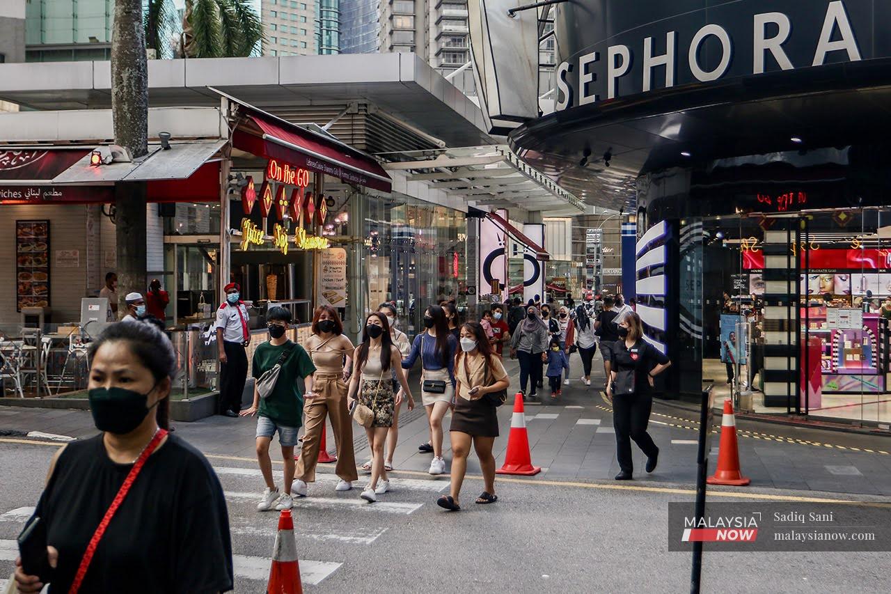 Pedestrians wearing face masks to prevent the spread of Covid-19 cross a road in the Bukit Bintang shopping district in Kuala Lumpur.