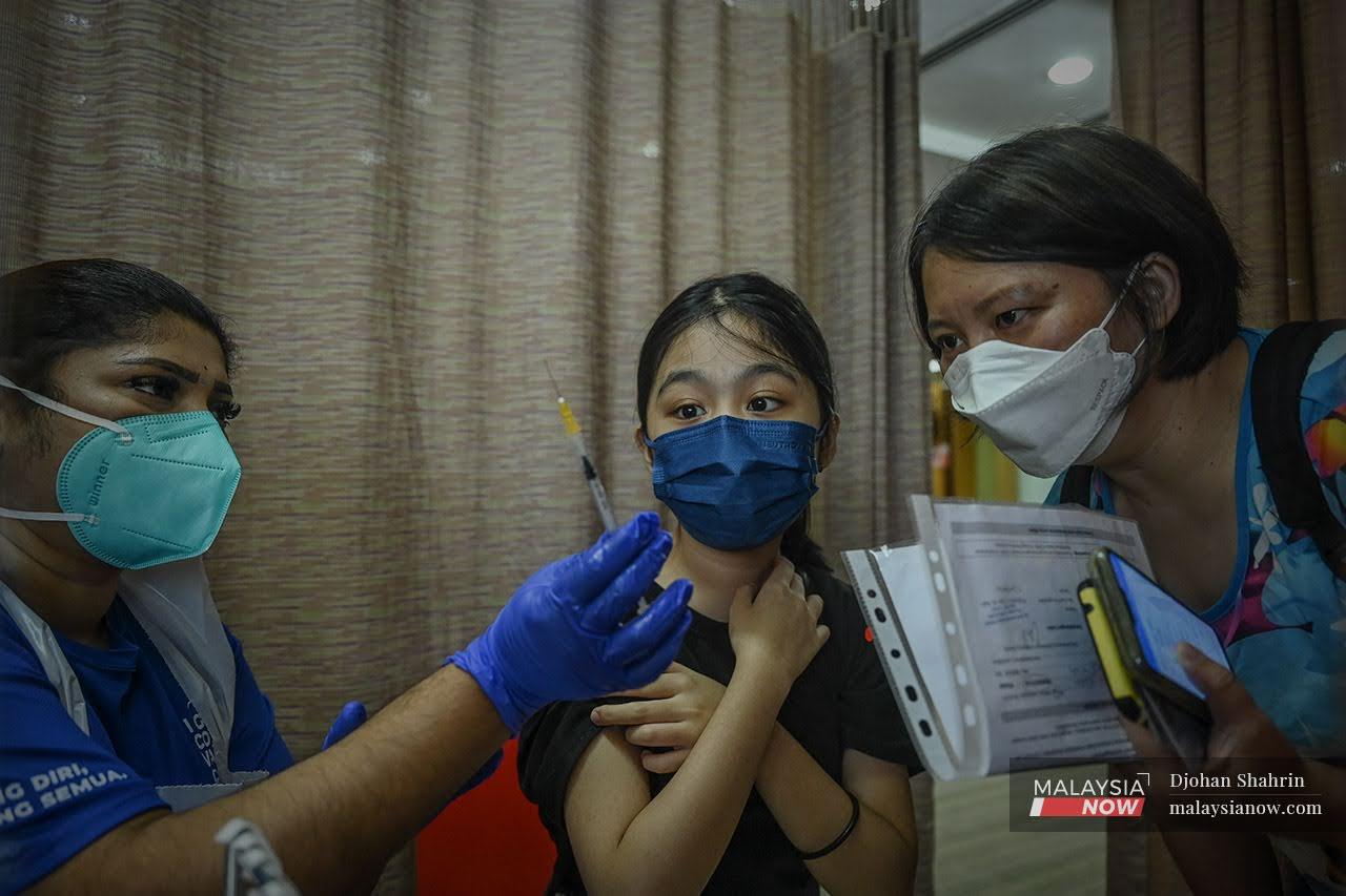 Petugas kesihatan menunjukkan jumlah dos pada picagari sebelum memberi suntikan vaksin Pfizer Bio-NTech kepada Chang Pei Ying, 13 di PPV KPJ Tawakkal, Jalan Pahang.
