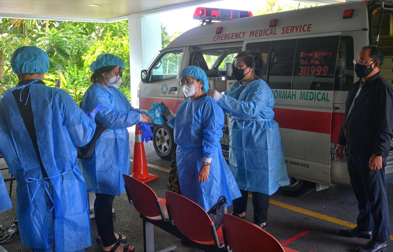 Family members of Sarawak Deputy Chief Minister James Jemut Masing wear personal protective equipment while waiting at the Normah Sarawak Medical Centre in Kuching after his death early today. Photo: Bernama
