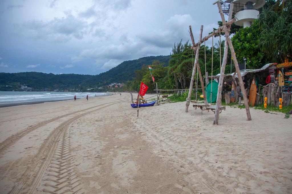 In this July 7 photo, tourists walk along a mostly empty Patong Beach on Phuket, southern Thailand. Tourism accounts for nearly a fifth of the economy and the impact of the pandemic has reverberated across various sectors, from restaurants to transportation. Photo: AP