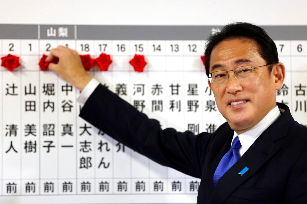 Japan's prime minister and ruling Liberal Democratic Party leader Fumio Kishida puts rosettes by successful general election candidates' names on a board at the party headquarters in Tokyo on Oct 31. Photo: AP