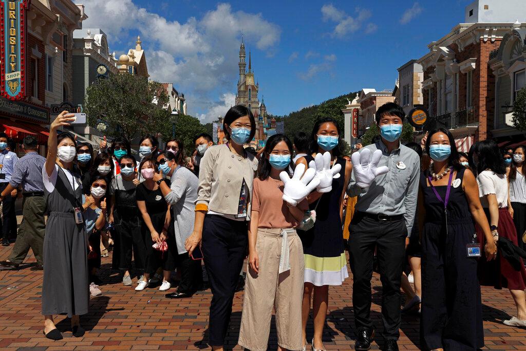 Employees and visitors wearing face masks to prevent the spread of the new coronavirus, take selfies at the Hong Kong Disneyland on June 18 2020. The park began barring new visitors from entering on Sunday, with everyone in the park required to take a Covid-19 test before leaving. Photo: AP