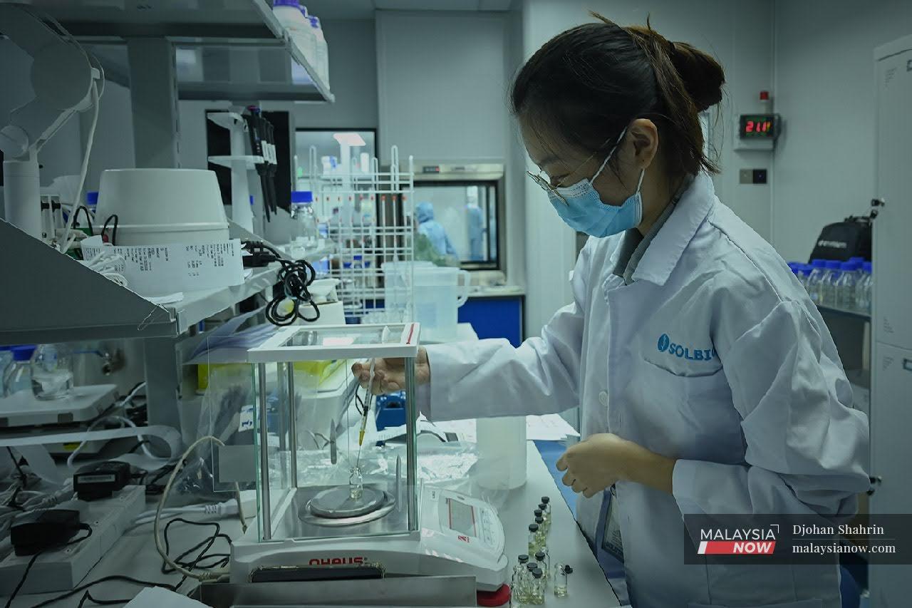 A lab technician runs a test for quality control on a vial of CanSino vaccine at Taman Teknologi Bukuit Jalil in Kuala Lumpur. Solution Biologics, a subsidiary of Solution Group Bhd which is a partner of CanSino Biologics, produces the CanSino jab using the company's facilities.