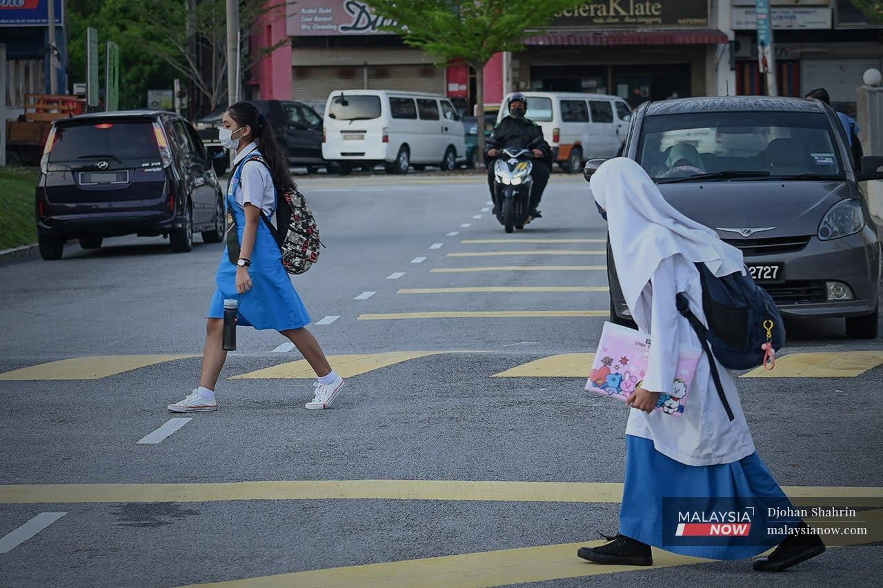 Dua orang murid sedang melintas jalan semasa berjalan kaki ke sekolah di Sekolah Menengah Kebangsaan Taman Kosas, Ampang.