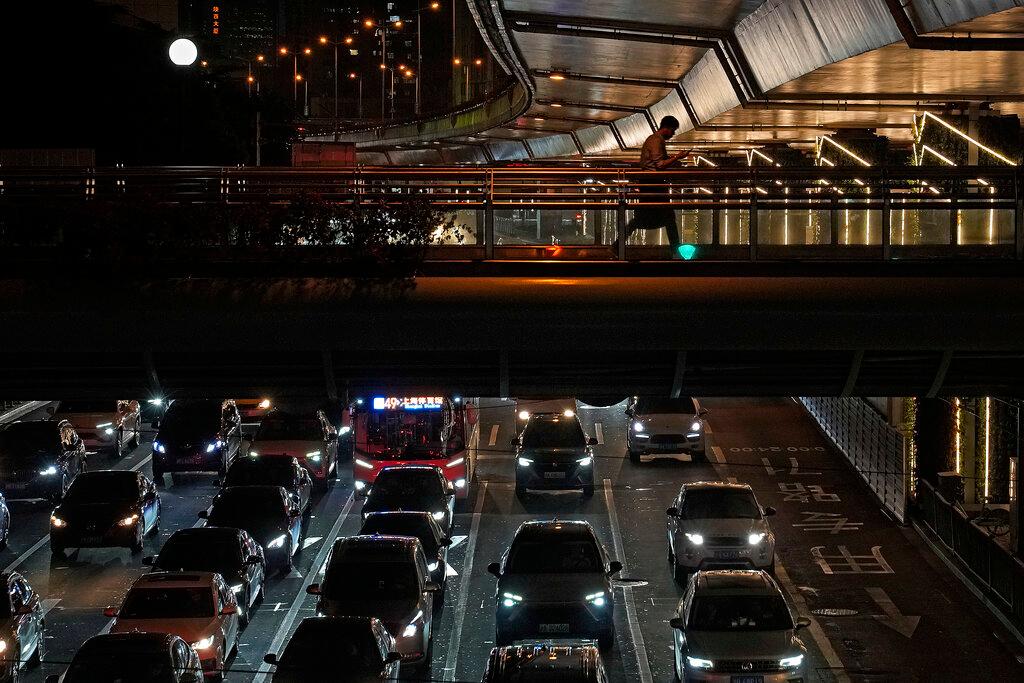 A man walks across a pedestrian bridge as motorists sit in heavy traffic below in Shanghai, China, Aug 25. Global carbon pollution this year has bounced back to almost 2019 levels, after a drop during pandemic lockdowns. Photo: AP
