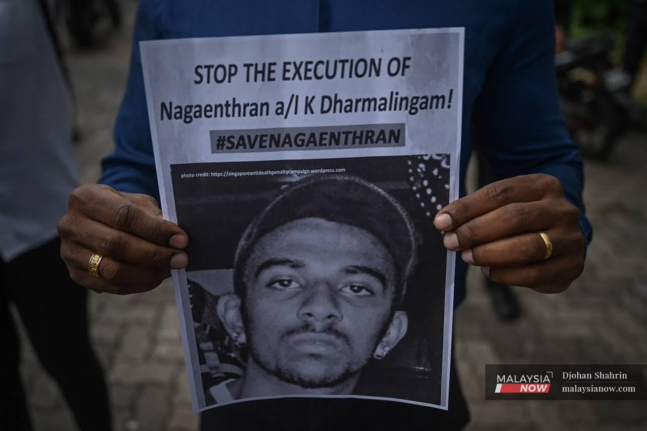 An activist holds up a poster showing Nagaenthran K Dharmalingam's picture at a gathering outside Parliament building on Wednesday.