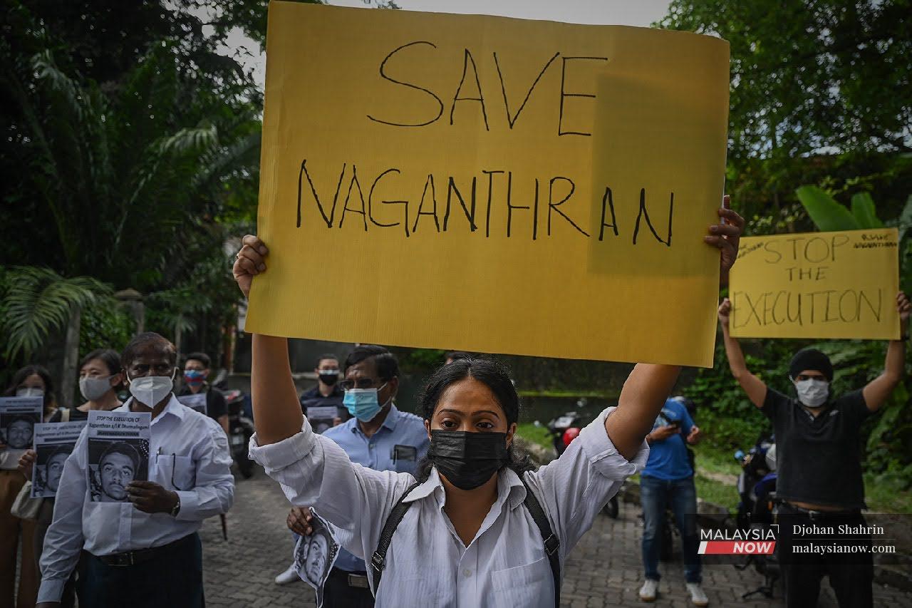 Aktivis NGO Sebaran Kasih, Angelia mengangkat plakad selamatkan Nagaenthran K Dharmalingam, seorang warga Malaysia cacat mental semasa himpunan penyerahan memorandum kepada Parlimen.